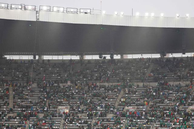 Mexican fans take shelter from the rain ahead of the 2026 World Cup round of 16 football match between Mexico and England at the Mexico City Stadium in Mexico City on July 5, 2026.  (Photo by Ulises RUIZ / AFP)