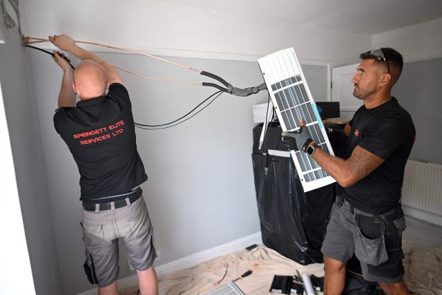 Engineers from Springett Elite Services install an air conditioning unit at a residential home in Croydon, south London, on July 1, 2026. A small but growing proportion of British households is embracing air conditioning (AC) to deal with increasingly hot summers. But the trend has attracted criticism, particularly from sustainability experts who argue it should not be the "default answer". (Photo by Justin TALLIS / AFP) / TO GO WITH Climate-weather-heatwave-Britain-airconditioning,FOCUS by Joe JACKSON