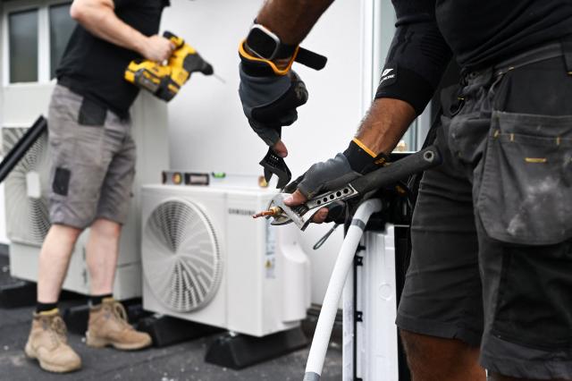 Engineers from Springett Elite Services install an air conditioning unit on the roof of a residential home in Croydon, south London, on July 1, 2026. A small but growing proportion of British households is embracing air conditioning (AC) to deal with increasingly hot summers. But the trend has attracted criticism, particularly from sustainability experts who argue it should not be the "default answer". (Photo by Justin TALLIS / AFP) / TO GO WITH Climate-weather-heatwave-Britain-airconditioning,FOCUS by Joe JACKSON
