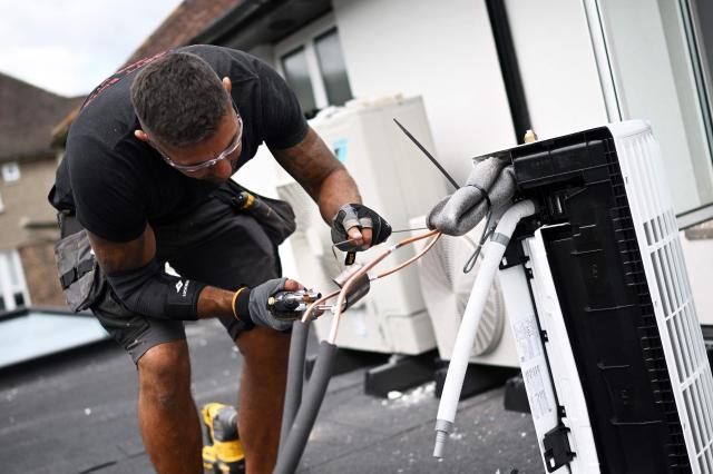An engineer from Springett Elite Services installs an air conditioning unit on the roof of a residential home in Croydon, south London, on July 1, 2026. A small but growing proportion of British households is embracing air conditioning (AC) to deal with increasingly hot summers. But the trend has attracted criticism, particularly from sustainability experts who argue it should not be the "default answer". (Photo by Justin TALLIS / AFP) / TO GO WITH Climate-weather-heatwave-Britain-airconditioning,FOCUS by Joe JACKSON