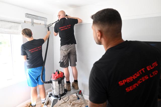 Engineers from Springett Elite Services drill the wall as they install an air conditioning unit at a residential home in Croydon, south London, on July 1, 2026. A small but growing proportion of British households is embracing air conditioning (AC) to deal with increasingly hot summers. But the trend has attracted criticism, particularly from sustainability experts who argue it should not be the "default answer". (Photo by Justin TALLIS / AFP) / TO GO WITH Climate-weather-heatwave-Britain-airconditioning,FOCUS by Joe JACKSON