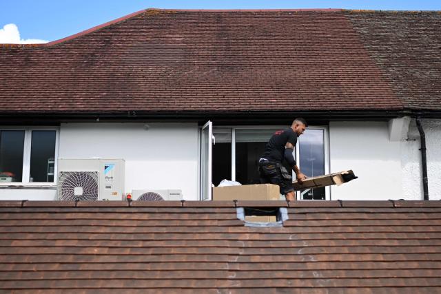 An engineer from Springett Elite Services installs an air conditioning unit on the roof of a residential home in Croydon, south London, on July 1, 2026. A small but growing proportion of British households is embracing air conditioning (AC) to deal with increasingly hot summers. But the trend has attracted criticism, particularly from sustainability experts who argue it should not be the "default answer". (Photo by Justin TALLIS / AFP) / TO GO WITH Climate-weather-heatwave-Britain-airconditioning,FOCUS by Joe JACKSON