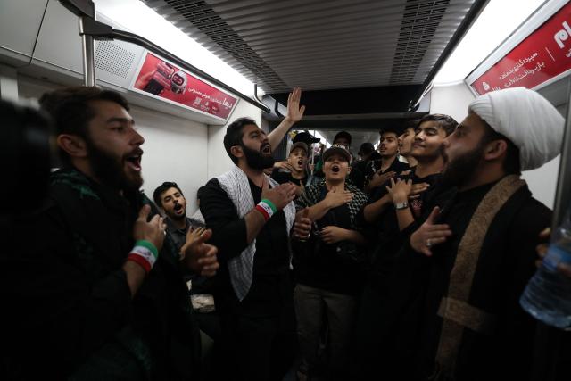 People chant abroad a train as they travel to join the funeral procession of Iran's slain Supreme Leader Ali Khamenei in Tehran July 6, 2026. Massive crowds are expected on July 6 for the funeral procession of late Iranian supreme leader Ali Khamenei in Tehran, with authorities hoping to avoid a repeat of the chaos that accompanied his predecessor's funeral. (Photo by ATTA KENARE / AFP) / 
