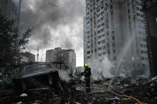 A rescuer extinguishes burning cars parked outside a multistorey residential building damaged following a Russian missile strike on the Ukrainian capital of Kyiv on July 6, 2026, amid the Russian invasion in Ukraine. Russia struck Ukraine's Kyiv region with ballistic missiles on July 6, killing at least eight people and wounding dozens, authorities said, on the eve of a NATO summit in Turkey. (Photo by Genya Savilov / AFP)