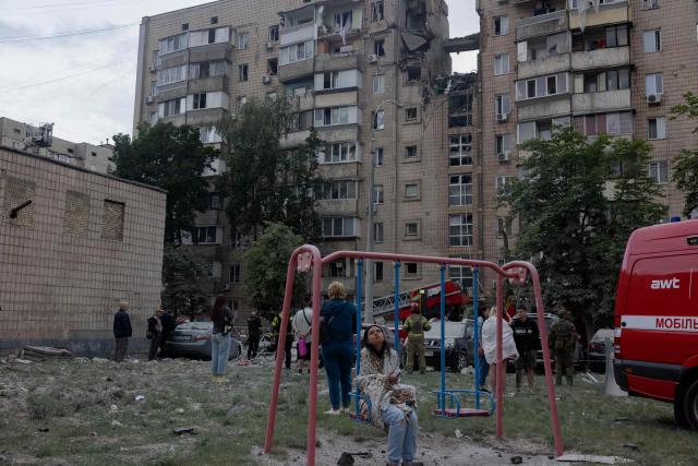 Local residents stand near a damaged residential building following a Russian missile strike on the Ukrainian capital of Kyiv on July 6, 2026, amid the Russian invasion in Ukraine. Russia struck Ukraine's Kyiv region with ballistic missiles on July 6, killing at least eight people and wounding dozens, authorities said, on the eve of a NATO summit in Turkey. (Photo by Tetiana DZHAFAROVA / AFP)