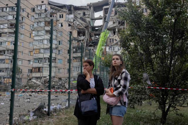 Local residents stand near a damaged residential building following a Russian missile strike on the Ukrainian capital of Kyiv on July 6, 2026, amid the Russian invasion in Ukraine. Russia struck Ukraine's Kyiv region with ballistic missiles on July 6, killing at least eight people and wounding dozens, authorities said, on the eve of a NATO summit in Turkey. (Photo by Tetiana DZHAFAROVA / AFP)
