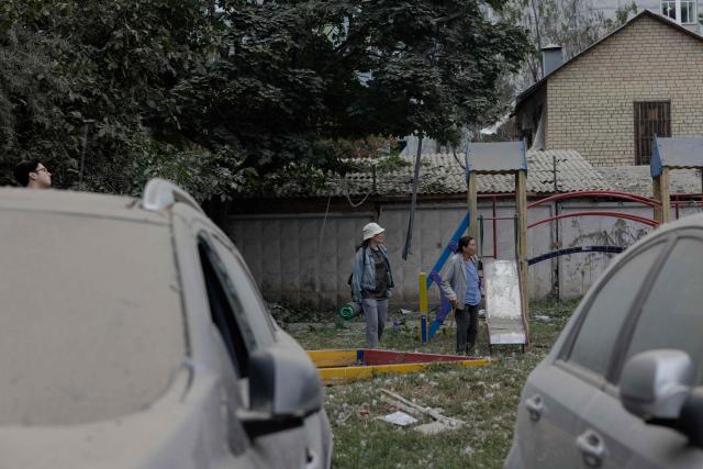 Local residents stand near a damaged residential building following a Russian missile strike on the Ukrainian capital of Kyiv on July 6, 2026, amid the Russian invasion in Ukraine. Russia struck Ukraine's Kyiv region with ballistic missiles on July 6, killing at least eight people and wounding dozens, authorities said, on the eve of a NATO summit in Turkey. (Photo by Tetiana DZHAFAROVA / AFP)