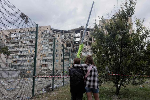 Local residents stand near a damaged residential building following a Russian missile strike on the Ukrainian capital of Kyiv on July 6, 2026, amid the Russian invasion in Ukraine. Russia struck Ukraine's Kyiv region with ballistic missiles on July 6, killing at least eight people and wounding dozens, authorities said, on the eve of a NATO summit in Turkey. (Photo by Tetiana DZHAFAROVA / AFP)