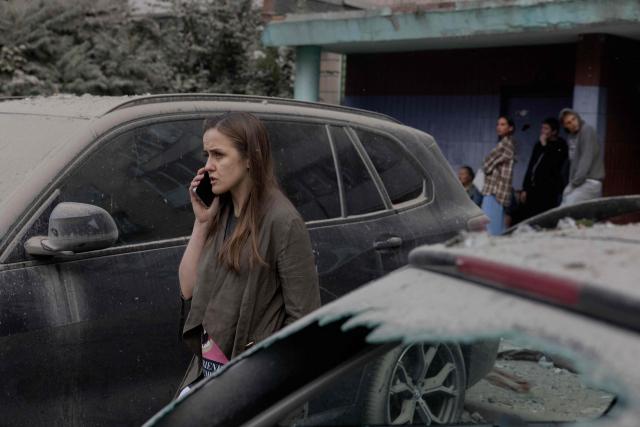 A woman talks on a phone next to damaged cars following a Russian missile strike on the Ukrainian capital of Kyiv on July 6, 2026, amid the Russian invasion in Ukraine. Russia struck Ukraine's Kyiv region with ballistic missiles on July 6, killing at least eight people and wounding dozens, authorities said, on the eve of a NATO summit in Turkey. (Photo by Tetiana DZHAFAROVA / AFP)