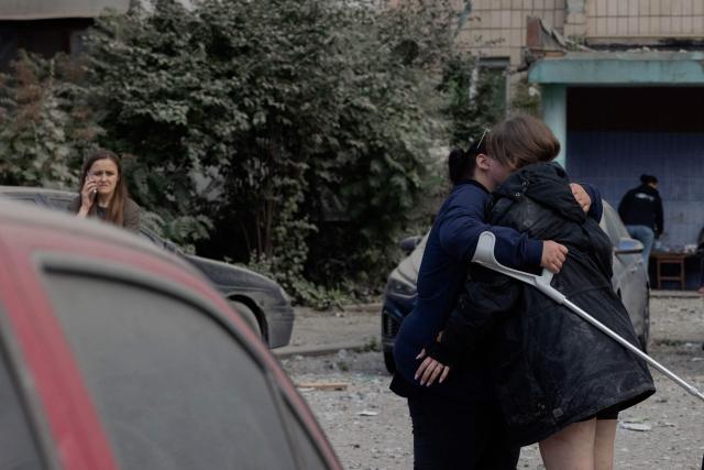 People hug near a damaged residential building following a Russian missile strike on the Ukrainian capital of Kyiv on July 6, 2026, amid the Russian invasion in Ukraine. Russia struck Ukraine's Kyiv region with ballistic missiles on July 6, killing at least eight people and wounding dozens, authorities said, on the eve of a NATO summit in Turkey. (Photo by Tetiana DZHAFAROVA / AFP)