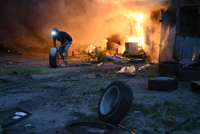A local resident moves wheels from burning garages outside a residential building following a Russian missile strike on the Ukrainian capital of Kyiv on July 6, 2026, amid the Russian invasion in Ukraine. Russia struck Ukraine's Kyiv region with ballistic missiles on July 6, killing at least eight people and wounding dozens, authorities said, on the eve of a NATO summit in Turkey. (Photo by Genya SAVILOV / AFP)