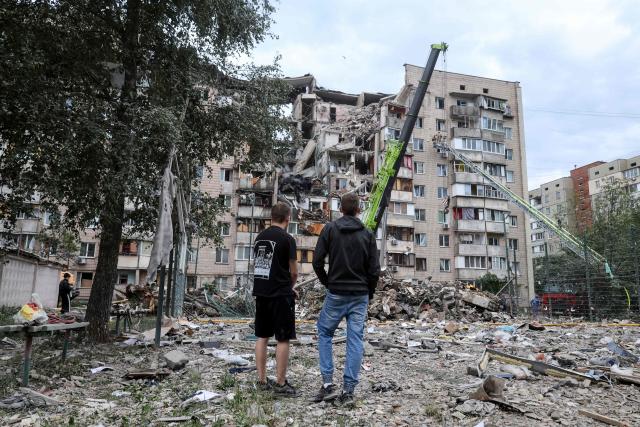 Local residents look at a residential building partially destroyed as a result of Russian missile strike on the Ukrainian capital of Kyiv on July 6, 2026, amid the Russian invasion in Ukraine. The death toll from Russian bombardment on the Kyiv region on July 6, has risen from eight to 10, authorities said, warning the number could rise further. (Photo by Serhii Okunev / AFP)