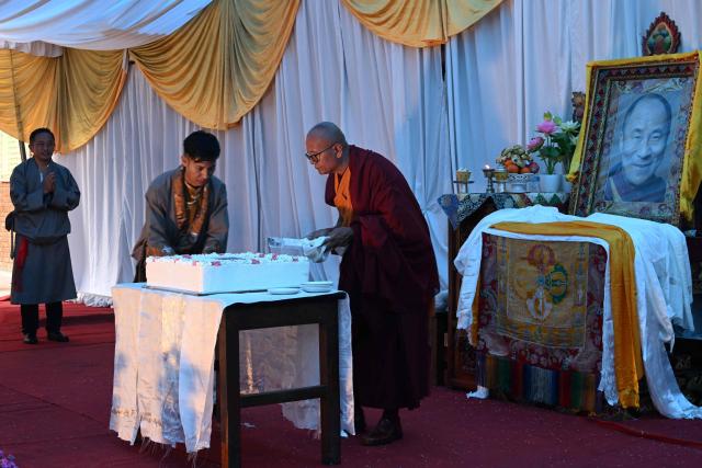 A Tibetan Buddhist monk in exile cuts a cake in front of Tibetan spiritual leader the Dalai Lama’s portrait during his 91st birthday celebrations at Namgyal School in Kathmandu on July 6, 2026. (Photo by PRAKASH MATHEMA / AFP)