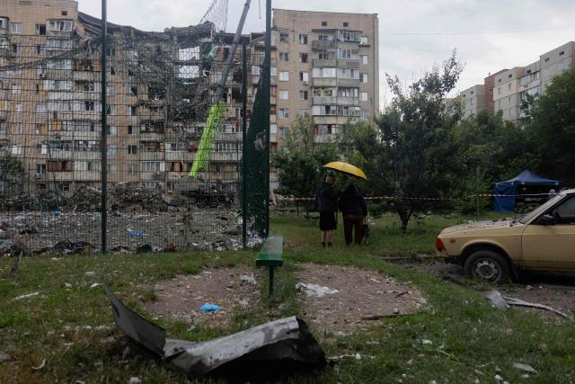Local residents look at a damaged residential building following a Russian missile strike on the Ukrainian capital of Kyiv on July 6, 2026, amid the Russian invasion in Ukraine. The death toll from Russian bombardment on the Kyiv region on July 6, has risen from eight to 10, authorities said, warning the number could rise further. (Photo by Tetiana DZHAFAROVA / AFP)