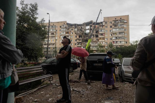 Local residents stand near a damaged residential building following a Russian missile strike on the Ukrainian capital of Kyiv on July 6, 2026, amid the Russian invasion in Ukraine. The death toll from Russian bombardment on the Kyiv region on July 6, has risen from eight to 10, authorities said, warning the number could rise further. (Photo by Tetiana DZHAFAROVA / AFP)