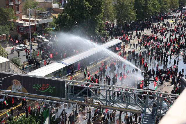 A water hose is used as people gather along a street for the funeral procession of Iran's slain Supreme Leader Ali Khamenei in Tehran July 6, 2026. Massive crowds are expected on July 6 for the funeral procession of late Iranian supreme leader Ali Khamenei in Tehran, with authorities hoping to avoid a repeat of the chaos that accompanied his predecessor's funeral. (Photo by AFP) / 