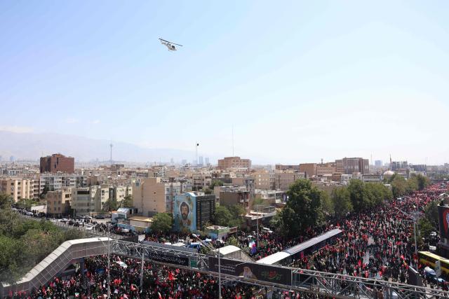 People gather along a street for the funeral procession of Iran's slain Supreme Leader Ali Khamenei in Tehran July 6, 2026. The funeral procession for Iran's late supreme leader Ali Khamenei began in Tehran on July 6, state television reported, as authorities prepared for crowds that could rival those that turned out for his predecessor nearly four decades ago. (Photo by AFP) / 