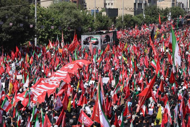 People gather along a street during the funeral procession of Iran's slain Supreme Leader Ali Khamenei in Tehran July 6, 2026. The funeral procession for Iran's late supreme leader Ali Khamenei began in Tehran on July 6, state television reported, as authorities prepared for crowds that could rival those that turned out for his predecessor nearly four decades ago. (Photo by ATTA KENARE / AFP) / 