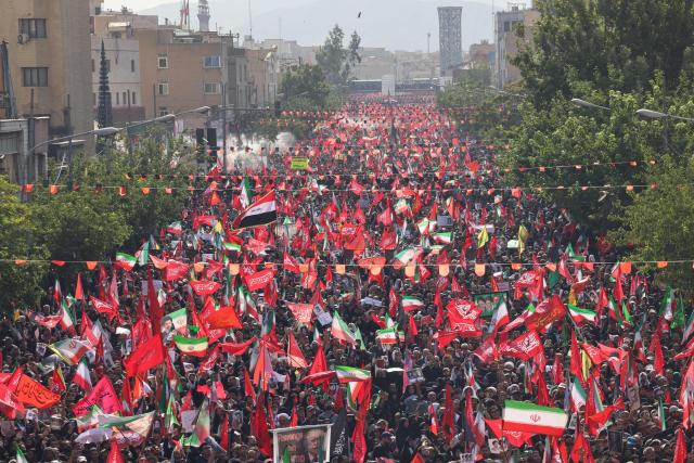 People gather along a street during the funeral procession of Iran's slain Supreme Leader Ali Khamenei and his family members in Tehran July 6, 2026. The funeral procession for Iran's late supreme leader Ali Khamenei began in Tehran on July 6, state television reported, as authorities prepared for crowds that could rival those that turned out for his predecessor nearly four decades ago. (Photo by ATTA KENARE / AFP) / 