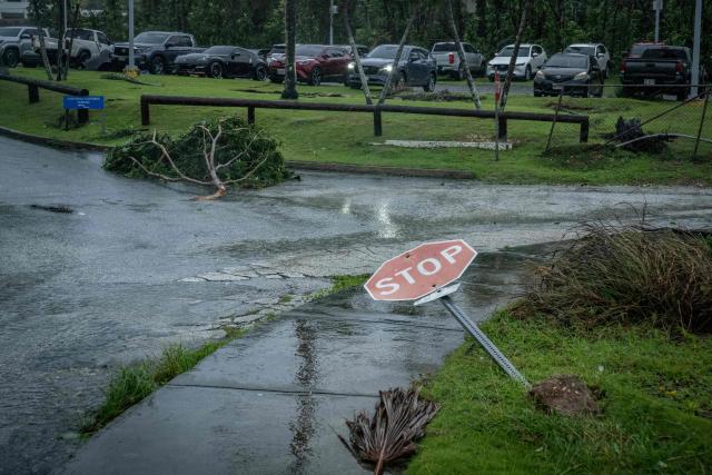 A traffic sign and broken tree lie on the ground after strong winds brought by Super Typhoon Bavi in Guam on July 6, 2026. A "super typhoon" with the force of a category-five hurricane tore through the US Pacific territories of Northern Marianas and Guam on July 6, with authorities saying they had received reports of "major" damage on the small island of Rota. (Photo by Yuichi YAMAZAKI / AFP)