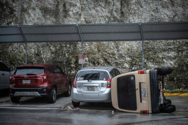 A car lies overturned after being flipped by strong winds brought by Super Typhoon Bavi in Guam on July 6, 2026. A "super typhoon" with the force of a category-five hurricane tore through the US Pacific territories of Northern Marianas and Guam on July 6, with authorities saying they had received reports of "major" damage on the small island of Rota. (Photo by Yuichi YAMAZAKI / AFP)