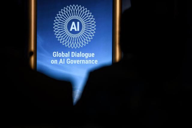 This photograph shows the logo of the first Global Dialogue on AI Governance displayed in Geneva on July 6, 2026. UN Secretary-General called for a global governance system to shape artificial intelligence for the good of humanity, warning against allowing the technology itself to "vibe-code" our future.  (Photo by Fabrice COFFRINI / AFP)