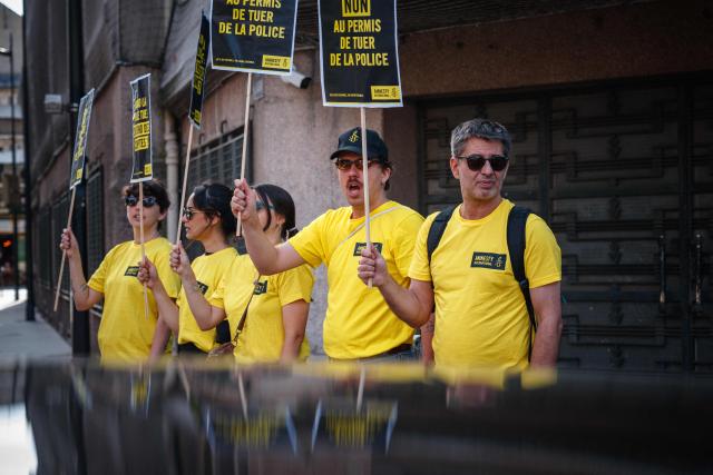 Activists gather holding placards which read as 'No to Police's license to kill' during a symbolic action by Amnesty International against the criminal justice and victim respect bill at the Ministry of the Interior branch in Paris on July 6, 2026. The bill on the presumption of self-defense for law enforcement, which is due to be debated on July 7, 2026 at the National Assembly, risks creating a "license to kill" and a form of blanket immunity for police officers and gendarmes, human rights defenders warn. (Photo by Dimitar DILKOFF / AFP)