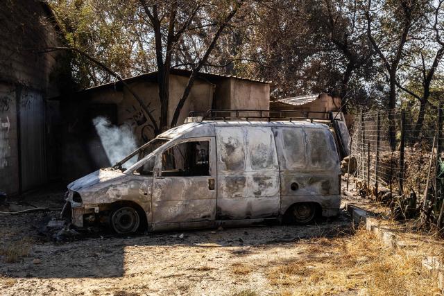 This photograph shows a burned vehicle in a residential area of the town of Ille sur Tet as a wildfire rages in the southern France department of Pyrenees-Orientales where 700 hundred firefighters backed by special aircraft battled to control a "gigantic" blaze spreading in a hard-to-reach remote area, with more than 10,000 local residents evacuated, near Perpignan on July 6, 2026. Wildfires raged across southern Europe, forcing thousands of people to evacuate their homes and prompting officials to ban spectators from a stage of the storied Tour de France cycling race. (Photo by Jean-Christophe MILHET / AFP)