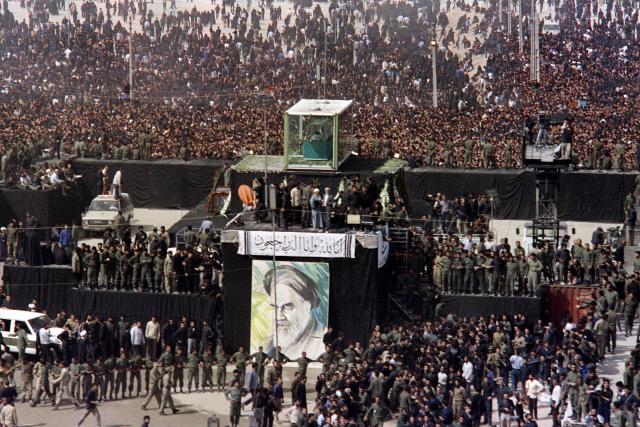 Mourners surround the body of Ayatollah Ruhollah Khomeini, displayed inside a glass coffin at the Mossalla prayer grounds in northeastern Tehran on June 5, 1989. Vast crowds gathered for the funeral procession of Iran's slain supreme leader Ali Khamenei in Tehran on July 6, 2026, with authorities estimating millions were on the streets in numbers that could rival those of his predecessor's farewell nearly four decades ago. Authorities are hoping to avoid a repeat of the chaos that marred the 1989 funeral of Khamenei's predecessor Ayatollah Ruhollah Khomeini, which drew an estimated 10 million people, according to state news agency IRNA. (Photo by CHRISTOPHE SIMON and PASCAL GEORGE / AFP)