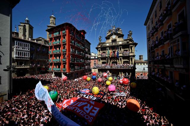 Revellers wave their red scarves during the "Chupinazo" (rocket launch) marking the official start of the San Fermin Festival in Plaza Consistorial outside the Town Hall of Pamplona in northern Spain on July 6, 2026. Thousands of people every year attend the week-long festival and its famous 'encierros' (bull runs) in which six bulls are released at 8:00 a.m. evey day starting July 7, to run from their corral to the bullring through the narrow streets of the old town over an 850 meters (yard) course while runners ahead of them try to stay close to the bulls without falling over or being gored. (Photo by Ander Gillenea / AFP)