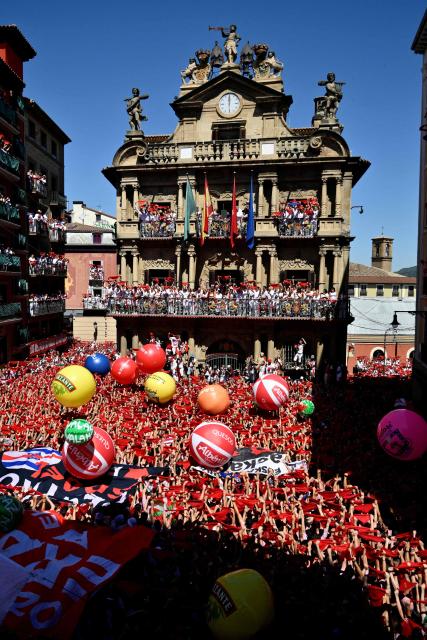 Revellers wave their red scarves during the "Chupinazo" (rocket launch) marking the official start of the San Fermin Festival in Plaza Consistorial outside the Town Hall of Pamplona in northern Spain on July 6, 2026. Thousands of people every year attend the week-long festival and its famous 'encierros' (bull runs) in which six bulls are released at 8:00 a.m. evey day starting July 7, to run from their corral to the bullring through the narrow streets of the old town over an 850 meters (yard) course while runners ahead of them try to stay close to the bulls without falling over or being gored. (Photo by Ander Gillenea / AFP)