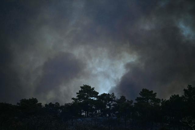Smoke obscures the sky as a wildfire rages in the southern France department of Herault as 700 hundred firefighters backed by special aircraft battled to control a "gigantic" blaze in nearby department of Pyrenees-Orientales, near the town of Carlencas-et-Levas on July 6, 2026. Wildfires raged across southern Europe, forcing thousands of people to evacuate their homes and prompting officials to ban spectators from a stage of the storied Tour de France cycling race. (Photo by Gabriel BOUYS / AFP)