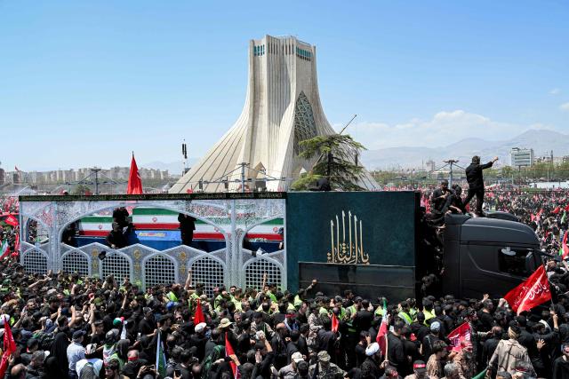 Mourners gather around the vehicle transporting the caskets of Iran's slain supreme leader Ali Khamenei and his family members during the funeral procession past Azadi Tower, at Azadi Square in Tehran on July 6, 2026. Massive crowds are expected on July 6 for the funeral procession of late Iranian supreme leader Ali Khamenei in Tehran, with authorities hoping to avoid a repeat of the chaos that accompanied his predecessor's funeral. (Photo by Wakil Kohsar / AFP) / 