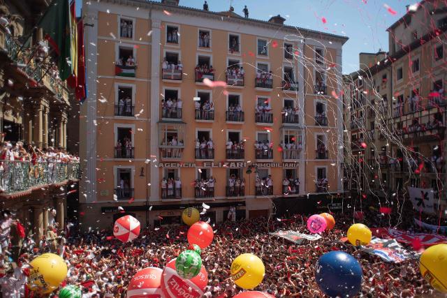 Revellers gather to celebrate during the "Chupinazo" (rocket launch) marking the official start of the San Fermin Festival in Plaza Consistorial outside the Town Hall of Pamplona in northern Spain on July 6, 2026. Thousands of people every year attend the week-long festival and its famous 'encierros' (bull runs) in which six bulls are released at 8:00 a.m. evey day starting July 7, to run from their corral to the bullring through the narrow streets of the old town over an 850 meters (yard) course while runners ahead of them try to stay close to the bulls without falling over or being gored. (Photo by JORGE GUERRERO / AFP)