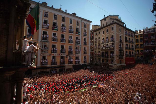 The "Pamplonesa" municipal music band performs during the "Chupinazo" (rocket launch) marking the official start of the San Fermin Festival in Plaza Consistorial outside the Town Hall of Pamplona in northern Spain on July 6, 2026. Thousands of people every year attend the week-long festival and its famous 'encierros' (bull runs) in which six bulls are released at 8:00 a.m. evey day starting July 7, to run from their corral to the bullring through the narrow streets of the old town over an 850 meters (yard) course while runners ahead of them try to stay close to the bulls without falling over or being gored. (Photo by JORGE GUERRERO / AFP)