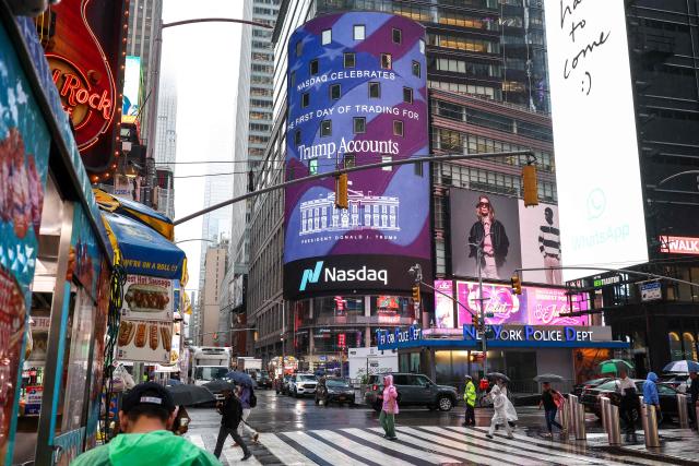 People walk near the Nasdaq headquarters as US President Donald Trump prepares to open the stock market remotely from The Oval Office in The White House, in New York, on July 6, 2026. The New York Stock Exchange and Nasdaq were opened remotely by US President Donald Trump to mark the launch of Trump investment accounts for children. (Photo by CHARLY TRIBALLEAU / AFP)