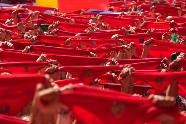 Revellers wave their red scarves during the "Chupinazo" (rocket launch) marking the official start of the San Fermin Festival in Plaza Consistorial outside the Town Hall of Pamplona in northern Spain on July 6, 2026. Thousands of people every year attend the week-long festival and its famous 'encierros' (bull runs) in which six bulls are released at 8:00 a.m. evey day starting July 7, to run from their corral to the bullring through the narrow streets of the old town over an 850 meters (yard) course while runners ahead of them try to stay close to the bulls without falling over or being gored. (Photo by Cesar MANSO / AFP)