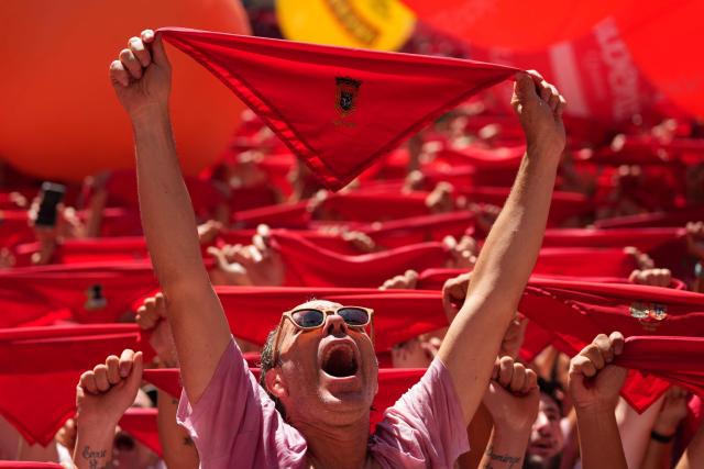 Revellers wave their red scarves during the "Chupinazo" (rocket launch) marking the official start of the San Fermin Festival in Plaza Consistorial outside the Town Hall of Pamplona in northern Spain on July 6, 2026. Thousands of people every year attend the week-long festival and its famous 'encierros' (bull runs) in which six bulls are released at 8:00 a.m. evey day starting July 7, to run from their corral to the bullring through the narrow streets of the old town over an 850 meters (yard) course while runners ahead of them try to stay close to the bulls without falling over or being gored. (Photo by Cesar MANSO / AFP)