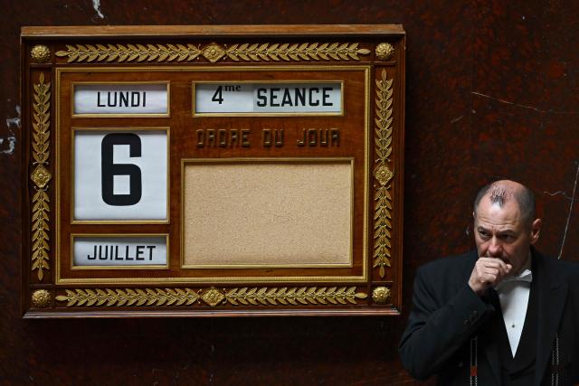 A bailiff stands next to a table showing the date and the session during a voting session on a no-confidence motion tabled by France's ecologist party Les Ecologistes at the National Assembly, France's lower house of parliament in Paris on July 6, 2026. (Photo by JULIEN DE ROSA / AFP)