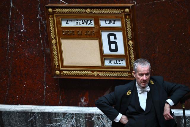 A bailiff stands next to a table showing the date and the session during a voting session on a no-confidence motion tabled by France's ecologist party Les Ecologistes at the National Assembly, France's lower house of parliament in Paris on July 6, 2026. (Photo by JULIEN DE ROSA / AFP)
