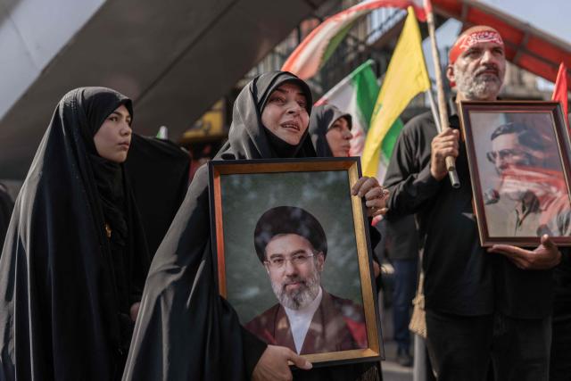 TOPSHOT - A mourner holds a portrait of Iran's supreme leader Ayatollah Mojtaba Khamenei as people attend the funeral pocession of Iran's slain supreme leader Ayatollah Ali Khamenei and his family members in Tehran on July 6, 2026. Vast crowds gathered for the funeral procession of Iran's slain supreme leader Ali Khamenei in Tehran on July 6, with authorities estimating millions were on the streets in numbers that could rival those of his predecessor's farewell nearly four decades ago. (Photo by AFP) / 