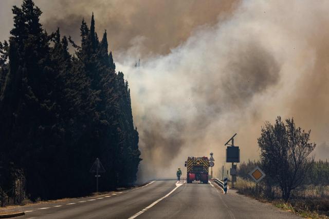 Firefighters fight against a wildfire raging in the southern France department of Pyrenees-Orientales near the town of Bouleternere, near Perpignan on July 6, 2026. 700 firefighters backed by special aircraft battled to control a "gigantic" blaze spreading in a hard-to-reach remote area near Ille-sur-Tet. Wildfires raged across southern Europe, forcing thousands of people to evacuate their homes and prompting officials to ban spectators from a stage of the storied Tour de France cycling race. (Photo by Jean-Christophe MILHET / AFP)