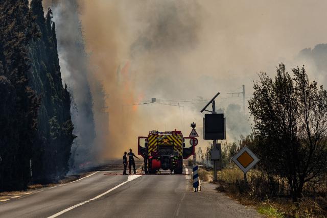 Firefighters fight against a wildfire raging in the southern France department of Pyrenees-Orientales near the town of Bouleternere, near Perpignan on July 6, 2026. 700 firefighters backed by special aircraft battled to control a "gigantic" blaze spreading in a hard-to-reach remote area near Ille-sur-Tet. Wildfires raged across southern Europe, forcing thousands of people to evacuate their homes and prompting officials to ban spectators from a stage of the storied Tour de France cycling race. (Photo by Jc Milhet / AFP)
