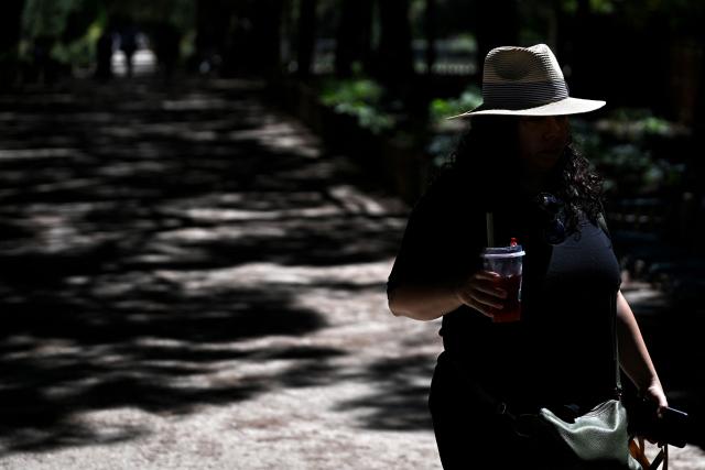 A pedestrian wearing a hat walks along a street in Bordeaux, south-western France on July 6, 2026, as France experiences another heatwave. (Photo by Christophe ARCHAMBAULT / AFP)