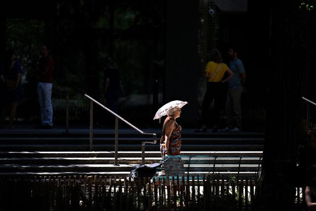 A pedestrian walks along a street carrying an umbrella to shelter from the sun in Bordeaux, south-western France on July 6, 2026, as France experiences another heatwave. (Photo by Christophe ARCHAMBAULT / AFP)