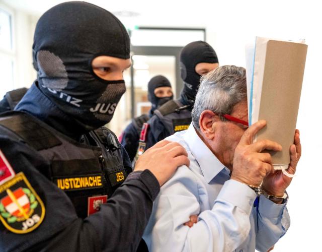 (FILES) In this file photo taken on June 1, 2026 the defendant, Syrian ex-general Khaled al-Halabi (R) covers his face as he is escorted in handcuffs for the start of his trial to the courtroom by justice officers at the Regional Criminal Court (Landesgericht fuer Strafsachen) in Vienna, Austria. A Syrian ex-general and a former police officer were found guilty by a Viennese court on July 6, 2026 of torturing opponents of Bashar al-Assad. The trial is the latest to see suspects from the Syrian civil war tried in European courts under the legal tool of universal jurisdiction, allowing judges to rule on alleged serious crimes committed abroad. (Photo by Joe Klamar / AFP) / Norway OUT