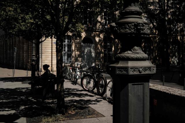 A woman sits in the shade during a summer heatwave in central Bordeaux, south-western France, on July 6, 2026. For the third time in six weeks, France is facing a surge in temperatures, with three-quarters of the country under a heatwave alert on July 7, 2026, just a few days after a historic heatwave. (Photo by Philippe LOPEZ / AFP)