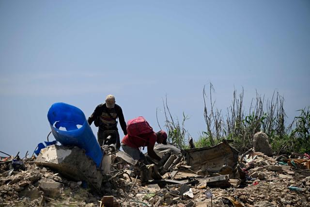 Men search for recyclable materials among debris from collapsed buildings in Caraballeda, La Guaira state, Venezuela, on July 6, 2026, following powerful earthquakes that struck the region. The earthquakes that struck Venezuela on June 24 have claimed the lives of at least 3,342 people, the Venezuelan government reported on July 5. (Photo by Federico PARRA / AFP)