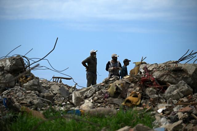 Men search for recyclable materials among debris in Caraballeda, La Guaira state, Venezuela, on July 6, 2026, following powerful earthquakes that struck the region. The earthquakes that struck Venezuela on June 24 have claimed the lives of at least 3,342 people, the Venezuelan government reported on July 5. (Photo by Federico PARRA / AFP)