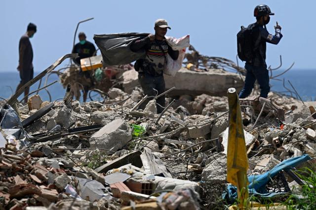 Men search for recyclable materials among debris from collapsed buildings in Caraballeda, La Guaira state, Venezuela, on July 6, 2026, following powerful earthquakes that struck the region. The earthquakes that struck Venezuela on June 24 have claimed the lives of at least 3,342 people, the Venezuelan government reported on July 5. (Photo by Federico PARRA / AFP)